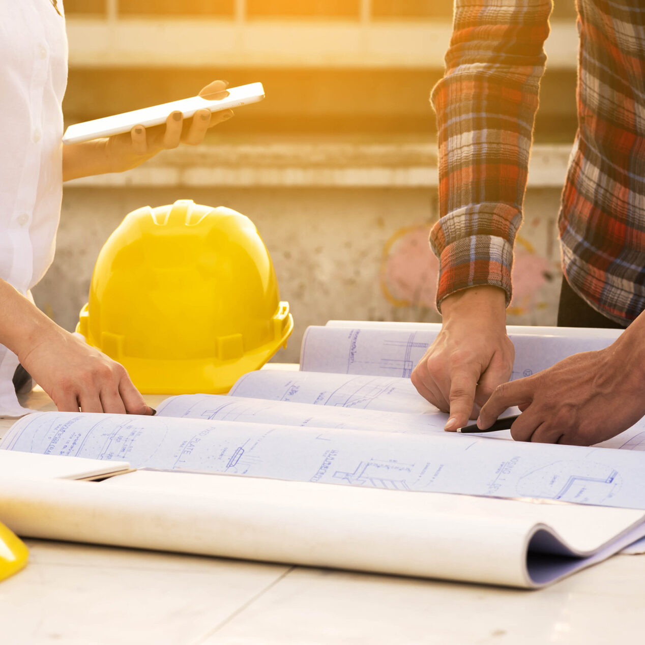 three construction engineers working outdoors in construction site with blueprint on table